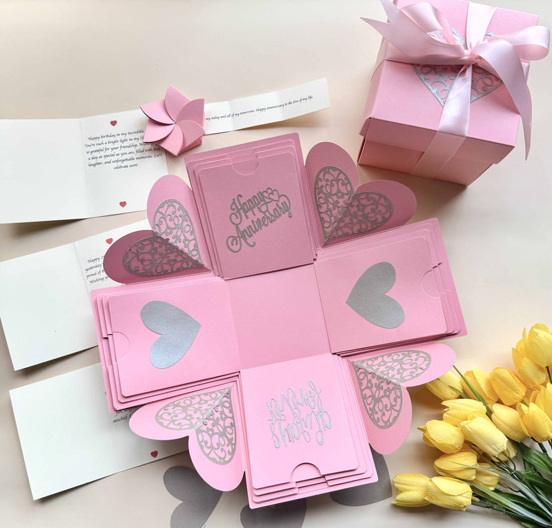 Explosion gift box for anniversary - Pink color with customized messages and wishes box wrapped in matching pink color bow. Product photo decorated with flowers and hearts
