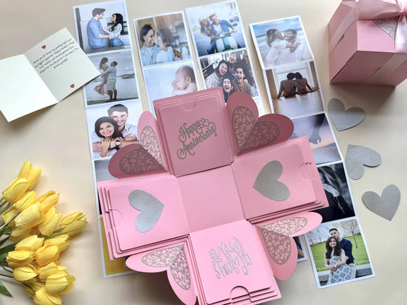 Pink anniversary explosion gift box with origami photo pockets, top-down view