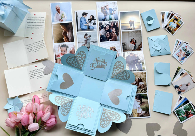 Flat-lay of blue birthday explosion gift box with photos and message layers