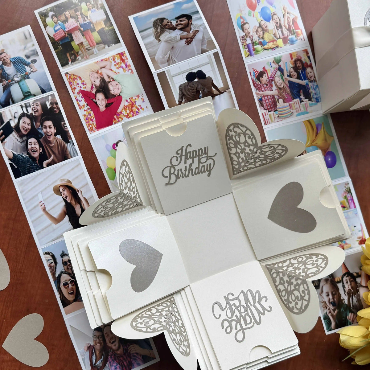 Flat-lay of white birthday explosion gift box with photos and message inserts
