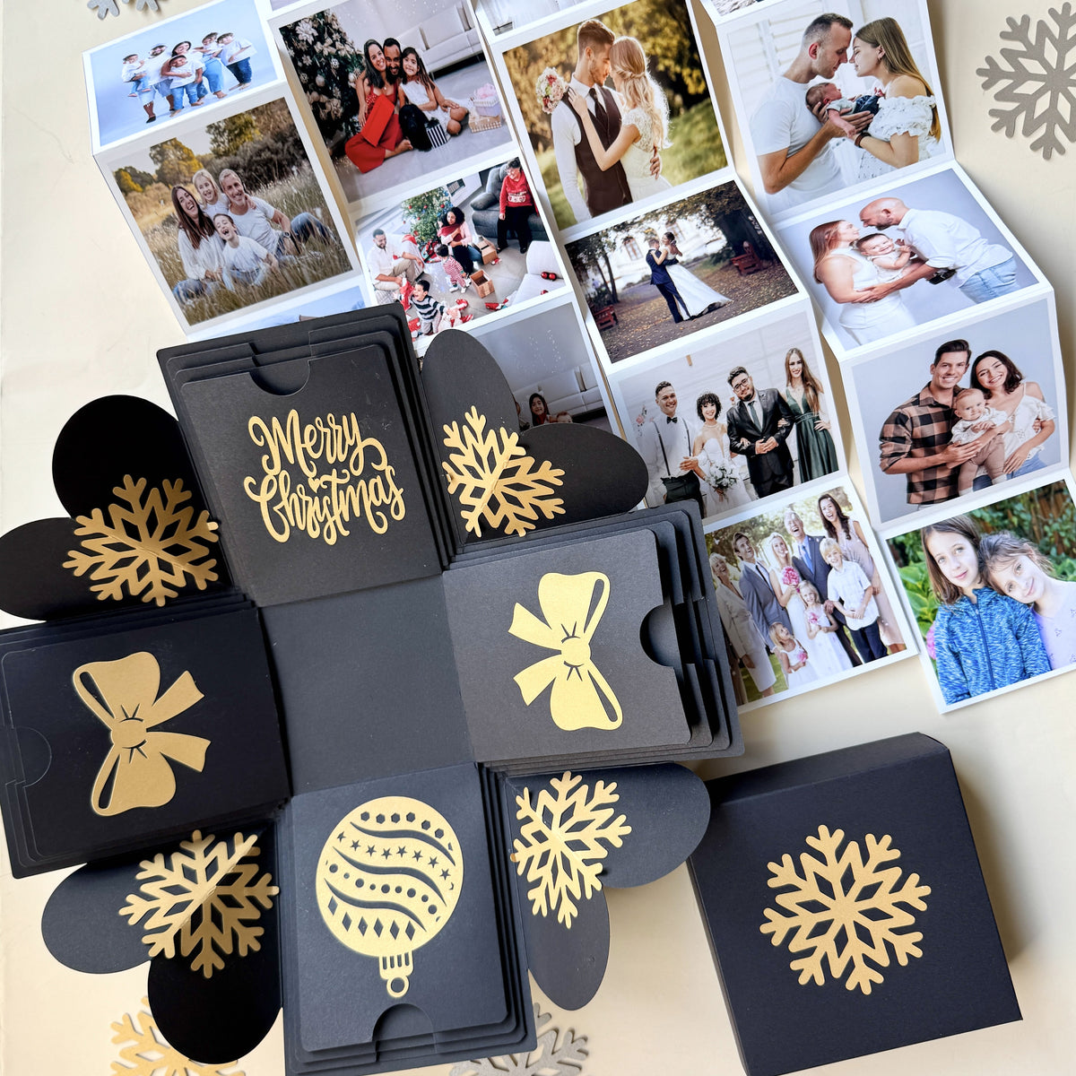Top-view black Christmas explosion gift box showing extended pull-out photo albums.