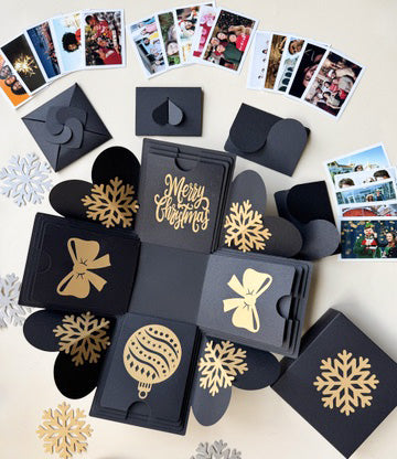 Flat lay of black Christmas explosion gift box opened with contents spread around it.