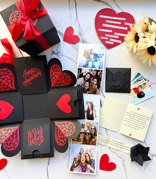 Red and black anniversary explosion gift box opened flat, showing photos and message cards