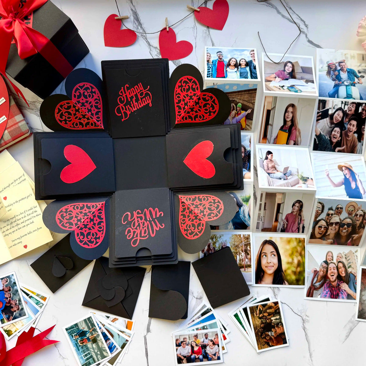 Close-up detail of black red birthday explosion gift box with custom photos and messages. All the contents spread across.

