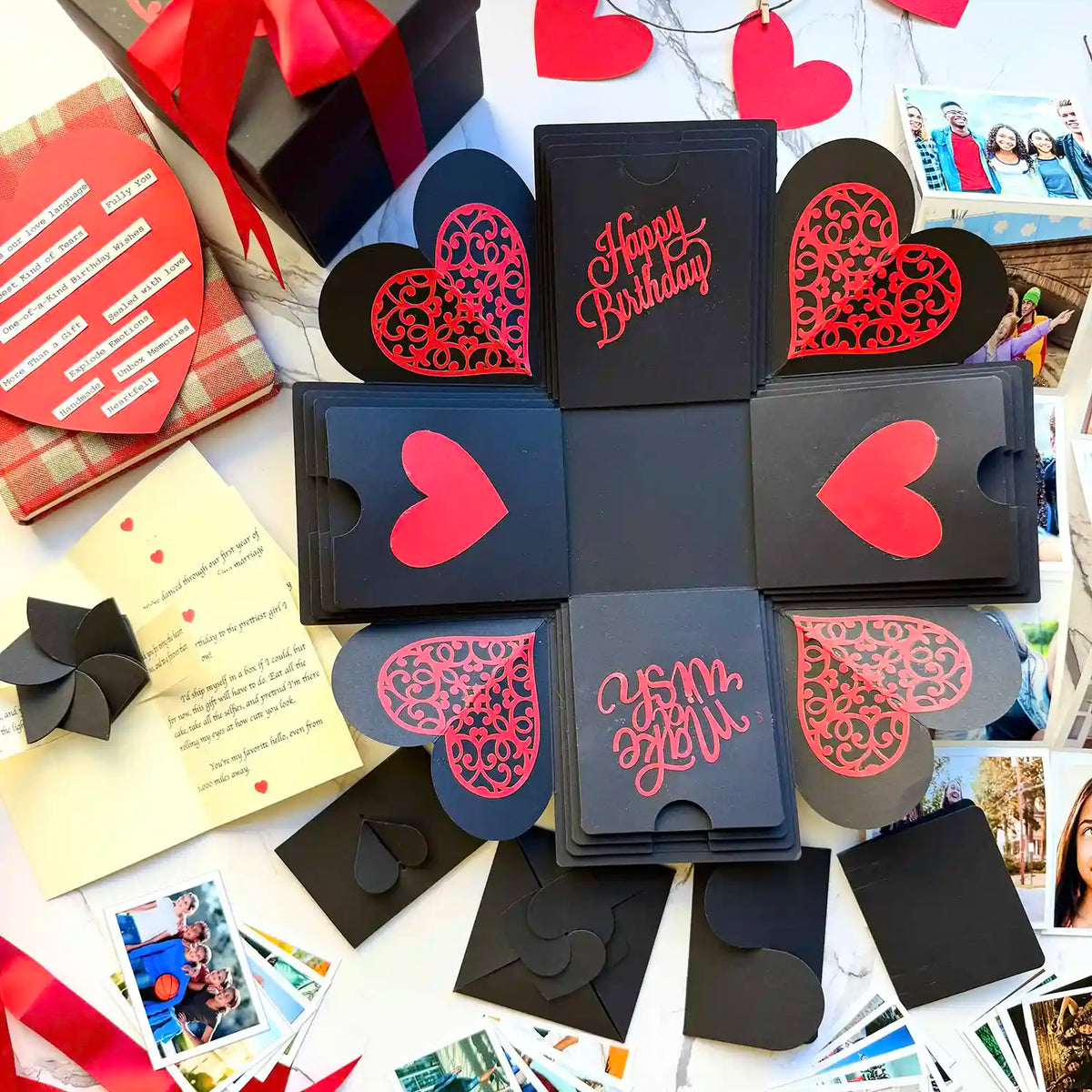 Open red and black birthday explosion gift box displaying pull-out albums and wishes