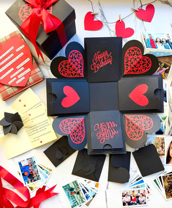 Open red and black birthday explosion gift box displaying pull-out albums and wishes