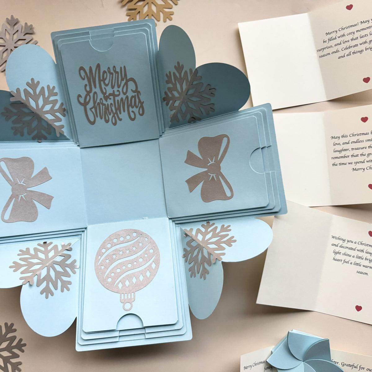 Top-view blue Christmas explosion gift box displaying extended pull-out photo albums.