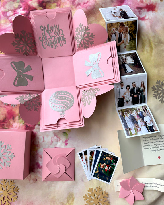 Flat lay of pink Christmas explosion gift box opened with contents spread around it.