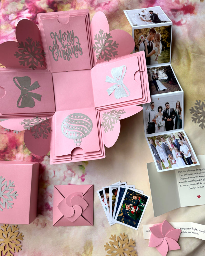 Flat lay of pink Christmas explosion gift box opened with contents spread around it.