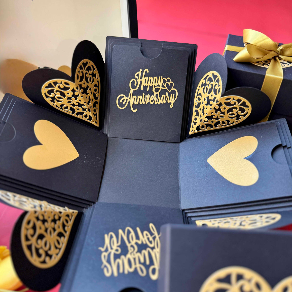 Fully opened black and gold explosion box with wrapped golden ribbon