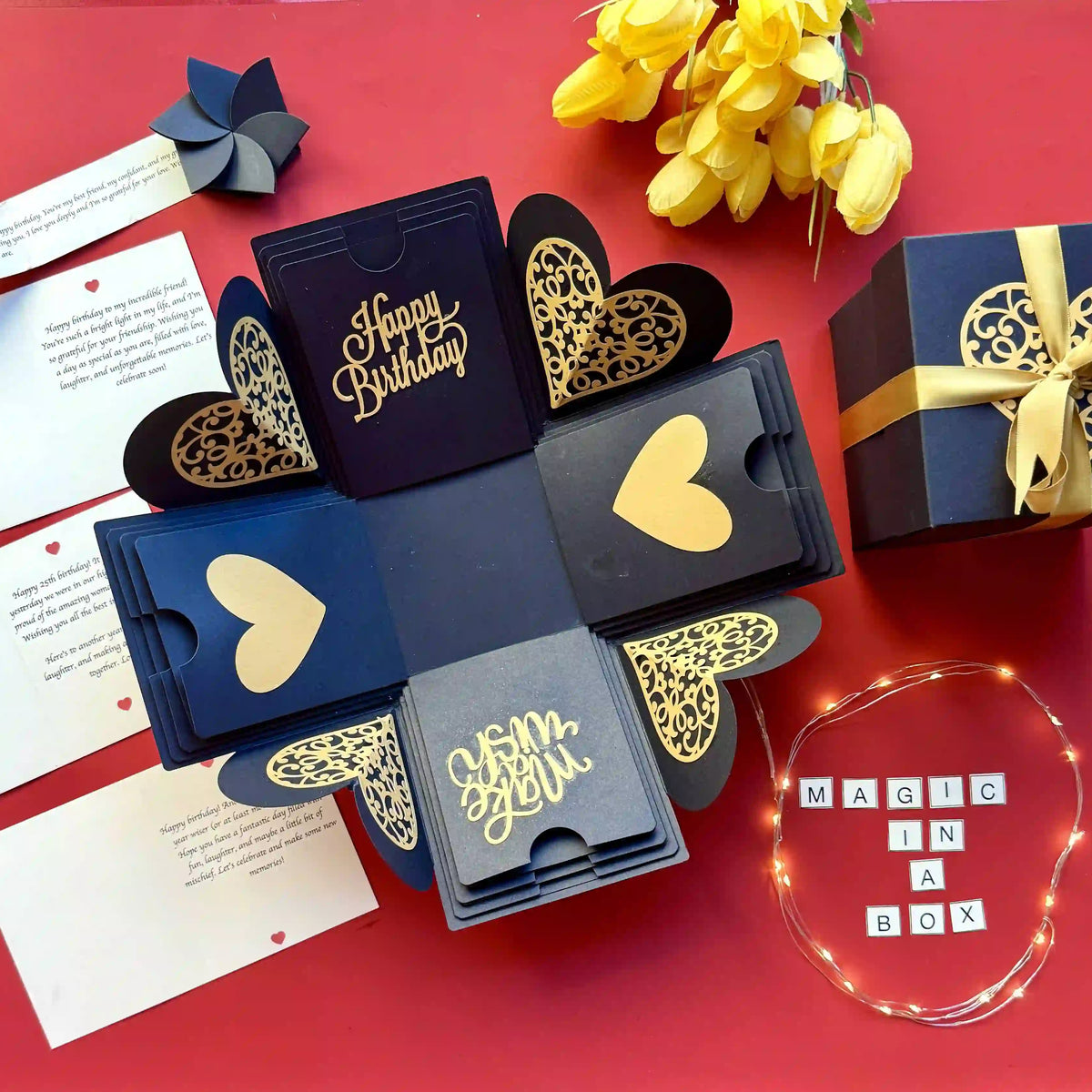 Flat-lay of black gold birthday explosion gift box with photos and message inserts