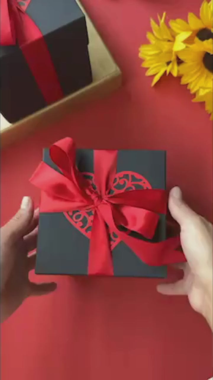 Vibrant red and black explosion gift box bursting open with photos, heartfelt messages, and pull-out albums. A luxurious handmade keepsake that captures love, joy, and celebration in every layer.