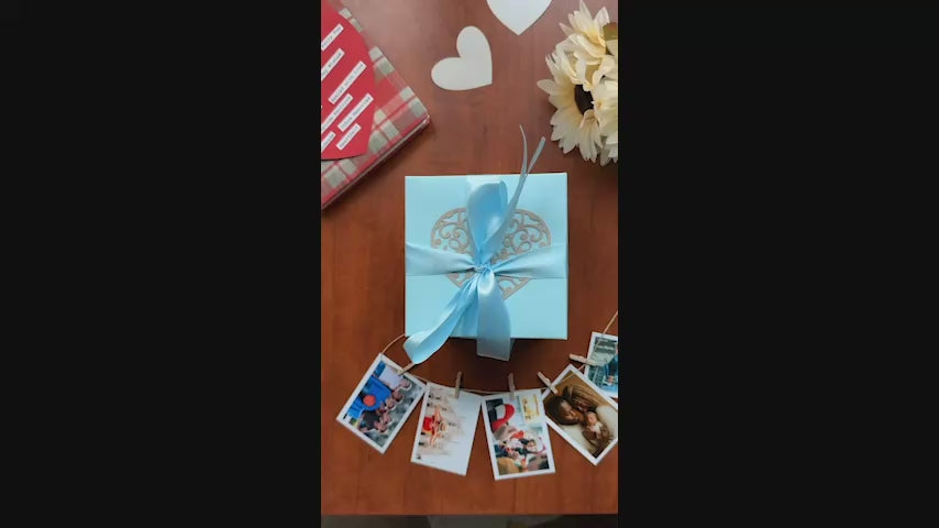 Video showing a black and red explosion gift box unfolding layer by layer, revealing photos, pull-out albums, and heartfelt message cards. The product demo highlights its customizable design and elegant craftsmanship, perfect for birthdays, anniversaries, and romantic gifting.